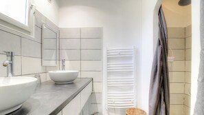 Ein modernes Badezimmer mit einem großen weißen Waschbecken, einem Spiegel und einem weißen Handtuchhalter.