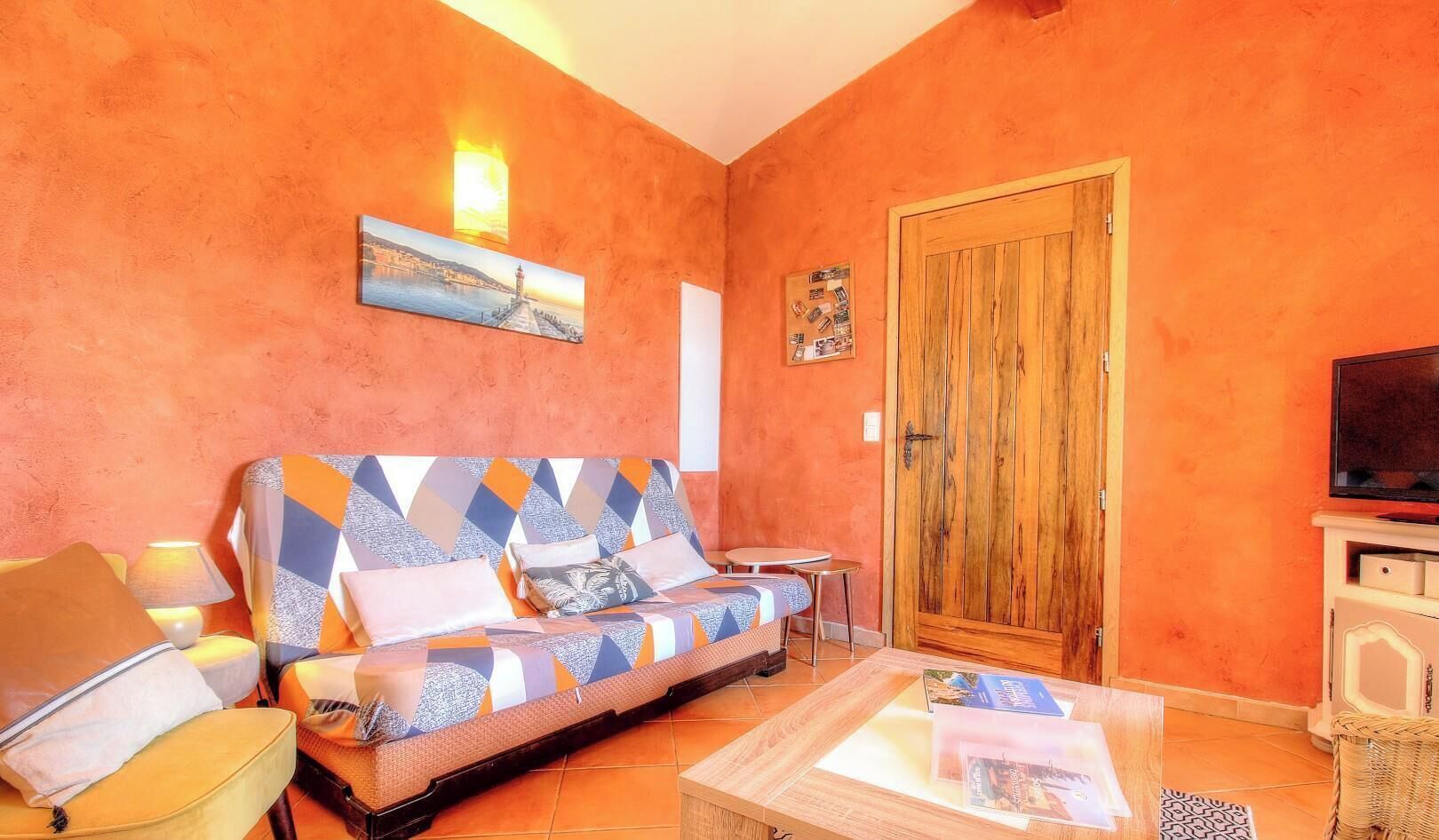 A room with a sofa, a small table, a wooden door, and a television.