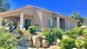 A two-story house with a covered patio, large windows, and a garden with rocks and plants. - Villa des oliviers - OLMETO (OLMETO)
