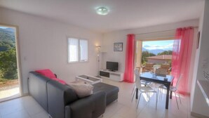 Ein modernes Wohnzimmer mit einer Couch, einem Fernseher, einem Esstisch und Stühlen.