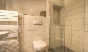 Ein Badezimmer mit Toilette, Waschbecken und Duschbereich.