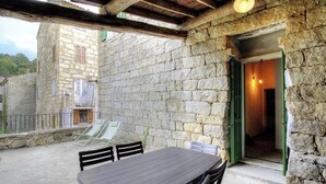 Ein Steinhaus mit Balkon, Tisch und Stühlen.