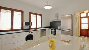 Una cuina moderna amb electrodomèstics integrats, una taula de dinar i un gerro groc.