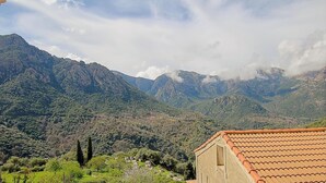 Paisatge montanyós amb un edifici amb teules vermelles.