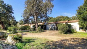 Una proprietà rurale con un vialetto sterrato, edifici bianchi con tetti in tegole rosse e vegetazione circostante.