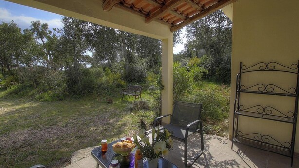 Una terrazza esterna con tavolo apparecchiato per la colazione, una panchina e una rastrelliera in metallo.