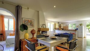 Un grand espace de vie comprenant une table à manger, des chaises, un canapé et une cuisine en arrière-plan.
