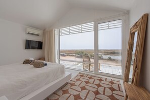 Une chambre avec une grande fenêtre, un lit, une télévision et un banc en bois.