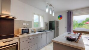 Una cucina moderna con microonde, forno e frigorifero. Si vede una finestra con vista su del verde all'esterno.