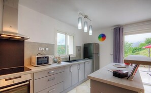 Eine moderne Küche mit Mikrowelle, Backofen und Kühlschrank. Ein Fenster bietet Blick auf Grünfläche.