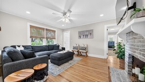 A modern living room with a sectional sofa, a fireplace, and a ceiling fan. - Charming Coastal Retreat with Live Oaks (Georgetown)