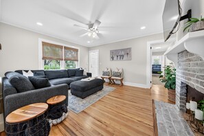 Ein modernes Wohnzimmer mit Ecksofa, Kamin und Deckenventilator.