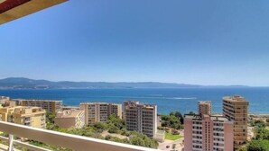 Un paysage urbain côtier avec de hauts immeubles, un ciel bleu dégagé et une vue sur la mer.