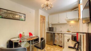 A compact kitchen with a dining table, chairs, a chandelier, and basic appliances. - Le 14802 - ALATA - Gîte (ALATA)