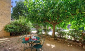 Zona d'estar a l'exterior amb una taula i cadires, envoltada de vegetació i una vista d'un cos d'aigua.