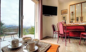 Ein Essbereich mit einem Tisch für vier Personen, einem roten Sofa und einem großen Fenster mit Blick ins Freie.