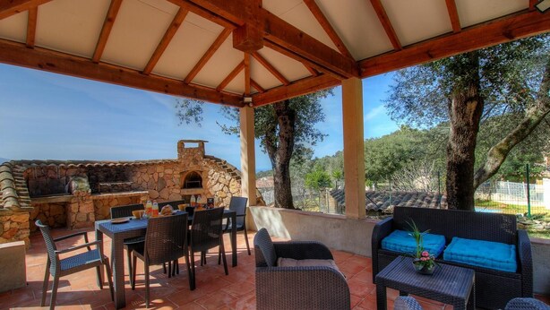 Eine Terrassengruppe im Freien mit Stein-Barbecue und Sitzgelegenheiten.
