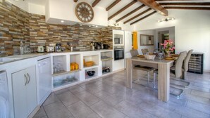 Eine moderne Küche mit Steinrückwand, Holzbalken und einem Essbereich mit Tisch und Stühlen.