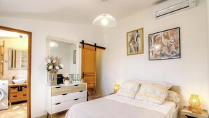 Ein Schlafzimmer mit einem Bett, Nachttischlampen, einem Schminktisch, einem Spiegel und Bildern an der Wand.
