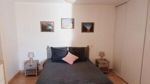 Quarto com uma cama, duas mesas de cabeceira e três quadros na parede.