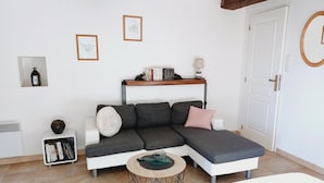 Uma sala de estar moderna com um sofá seccional, uma mesa de centro redonda, uma estante e quadros nas paredes.