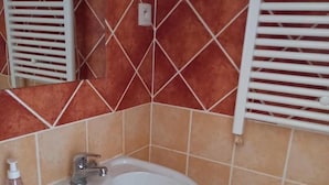 Um banheiro com pia branca, espelho e porta-toalhas.