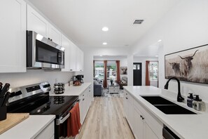 A modern kitchen with white cabinets, a stainless steel stove, and a black sink.