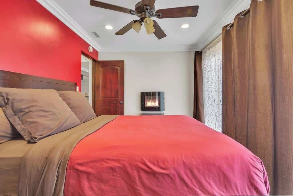 Une chambre à coucher avec un lit, un ventilateur de plafond, une cheminée et une porte.