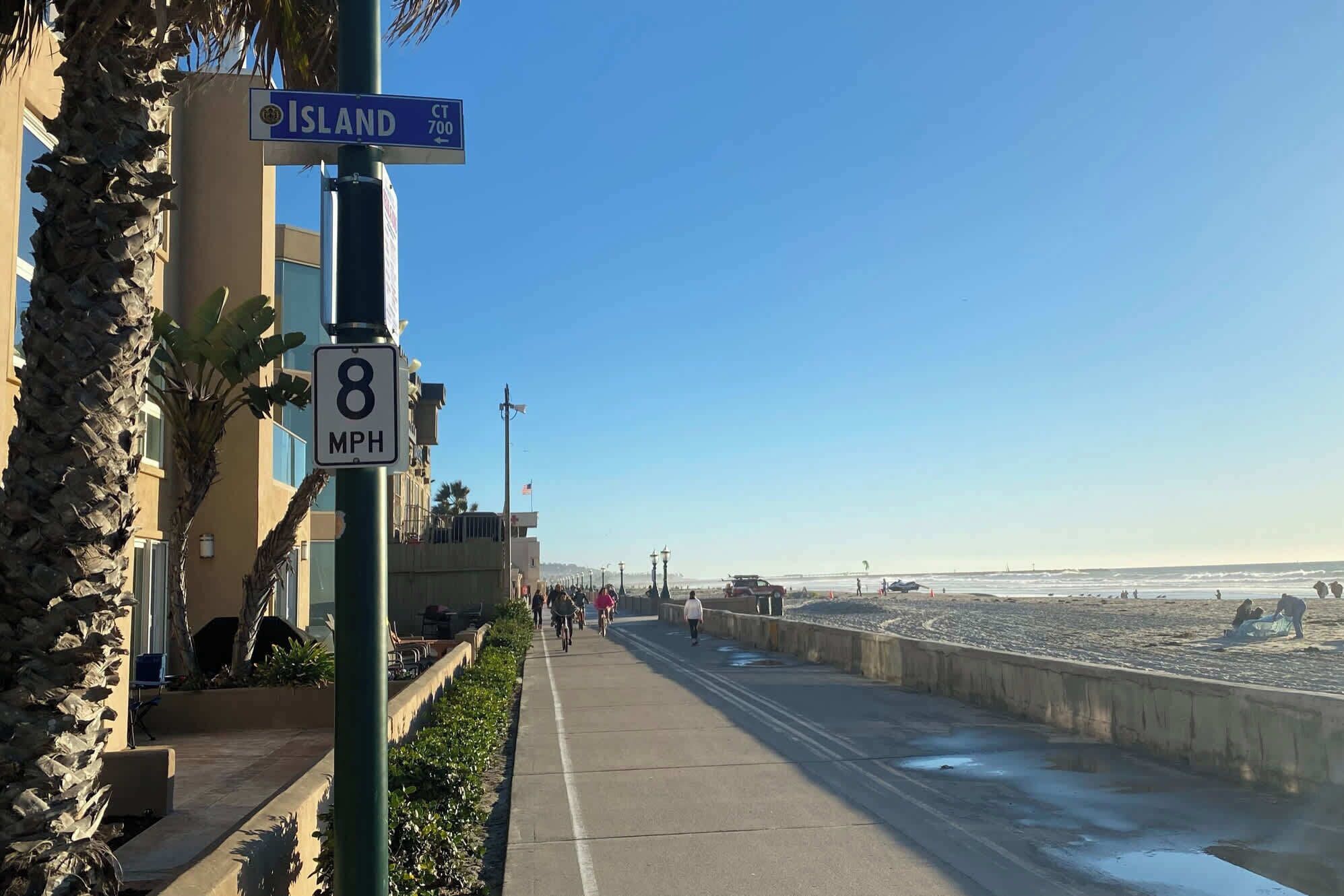 Eine Küstenstraße mit Geschwindigkeitsbegrenzungsschild, Straßenschild und Blick auf den Strand.