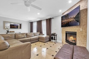 A modern living room with a sectional sofa, a fireplace, and a large TV mounted on the wall. - RMB I: Island Beach Condo; 2Br, Sleeps 6-10 (San Diego)