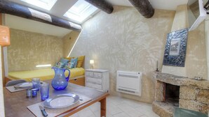 Ein gemütliches Zimmer mit einem Bett, einem Tisch mit einer Vase, einem Kamin und einem Oberlicht.