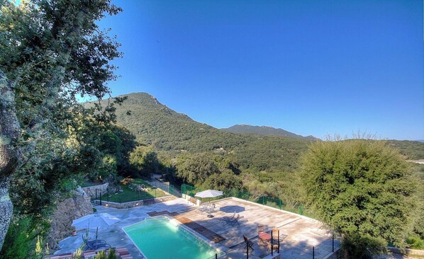 Ein Poolbereich mit Blick auf eine Berglandschaft, umgeben von viel Grün.