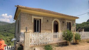 A stone house with a white picket fence, two doors, and a small porch. - Villa Charlain - PIETROSELLA (PIETROSELLA)