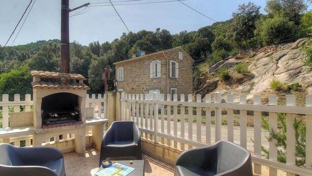 A stone building with a balcony, outdoor seating, and a barbecue grill. - Villa Charlain - PIETROSELLA (PIETROSELLA)