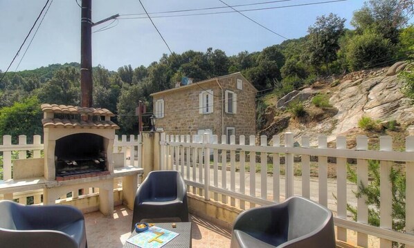 Ein Steinhaus mit Balkon, Außenbereich und Grill.
