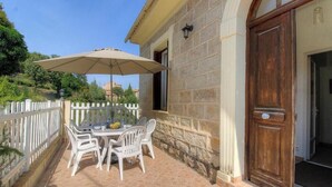 A patio with a table and chairs, a wooden door, and a white fence. - Villa Charlain - PIETROSELLA (PIETROSELLA)