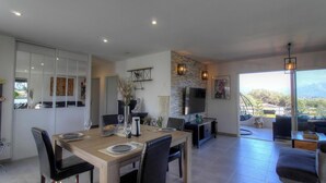 A spacious living area with a dining table, chairs, a TV, and a view of the outdoors. - Le Spurtone - ALATA - Gîte (ALATA)