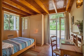 Une chambre à coucher comprenant un lit, une chaise, un bureau et une porte coulissante donnant sur un balcon.