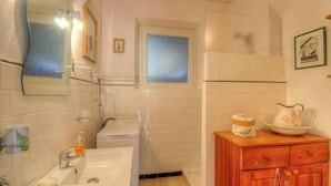 Un bany amb un lavabo, mirall, penjador de tovalloles i una finestra.