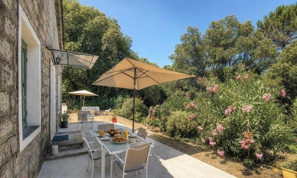 An outdoor patio with a table set for dining, surrounded by greenery and trees. - Funtanedda - LEVIE - Gîte (LEVIE)