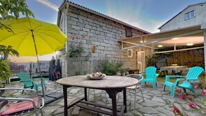 A patio with a stone table, chairs, and a yellow umbrella. - A MOLINA - ZICAVO - Gîte (ZICAVO)