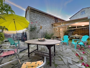 A patio with a stone table, chairs, and a yellow umbrella. - A MOLINA - ZICAVO - Gîte (ZICAVO)