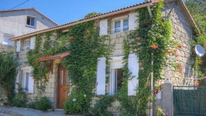A stone house with a tiled roof, a wooden door, and windows with shutters. - A MOLINA - ZICAVO - Gîte (ZICAVO)