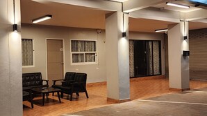Un hall con zona de estar, una puerta y una ventana con cortinas.