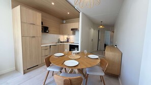 A compact kitchen with wooden cabinets, a dining table set for four, and a small island. - Renovated apartment with shared pool and parking (LA COUARDE SUR MER)