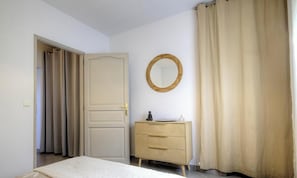 A bedroom with a bed, a dresser, a mirror, and a door. - Le 62061 - TAGLIO ISOLACCIO (TAGLIO ISOLACCIO)