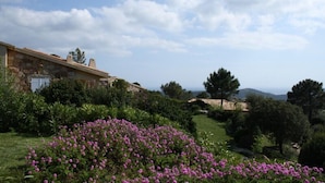 Un edificio de piedra con jardín y vistas al mar.