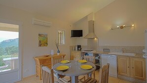 Una cocina moderna con comedor, un televisor montado sobre la encimera y vistas al exterior.