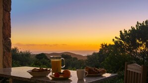 Una mesa con alimentos para el desayuno y una vista panorámica del atardecer.