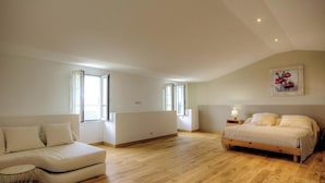 A spacious bedroom with a large bed, a sofa, and two windows providing natural light. - Little paradise - ROGLIANO (ROGLIANO)